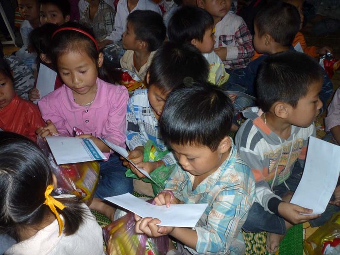 Các em học sinh mẫu giáo chậm rãi đánh vần từng chữ hàng chữ báo Giáo dục Việt Nam ghi trên phong bì tiền của mình